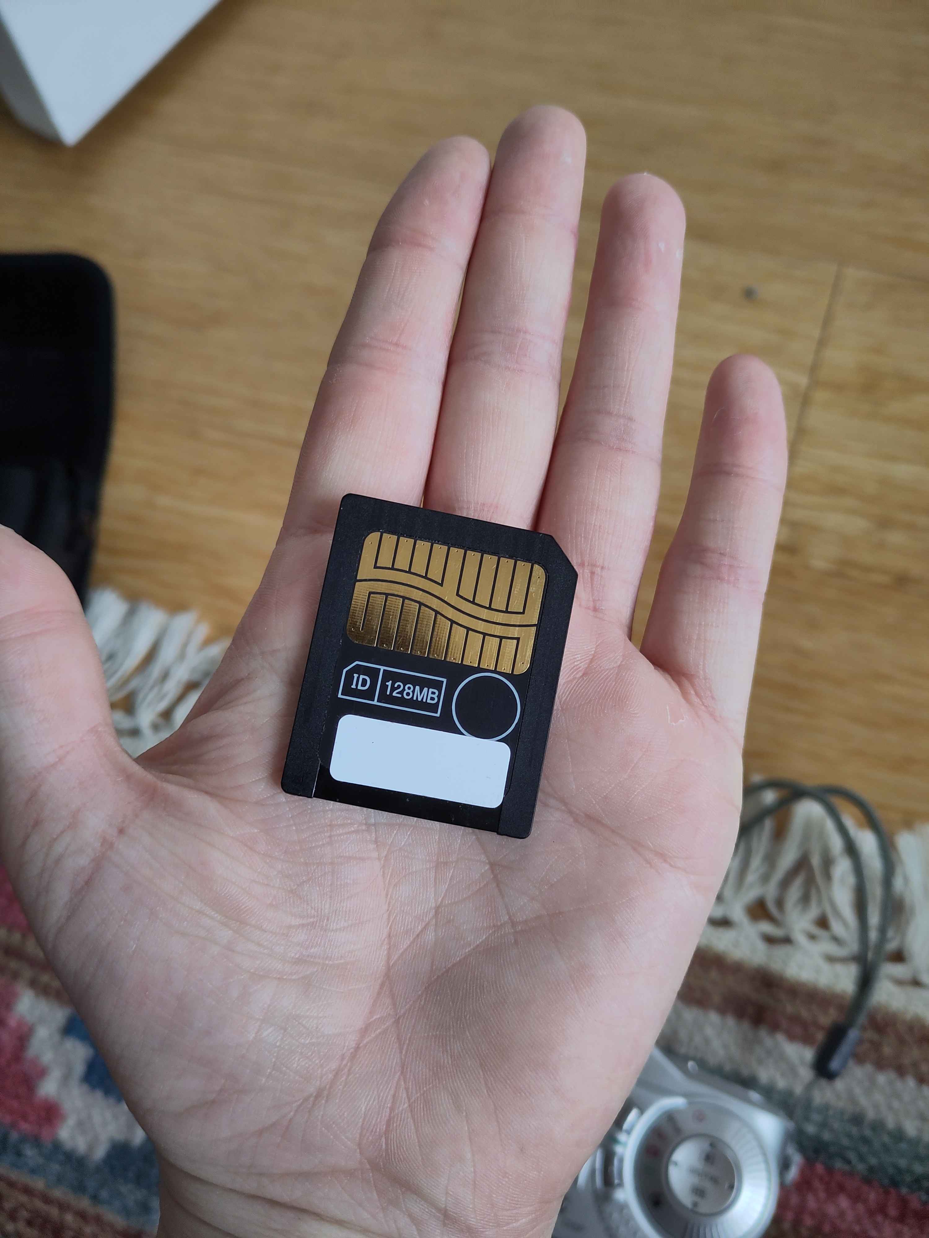 A SmartMedia card, similar to an SD card but twice the size, its metal contacts are cut in a wavy pattern