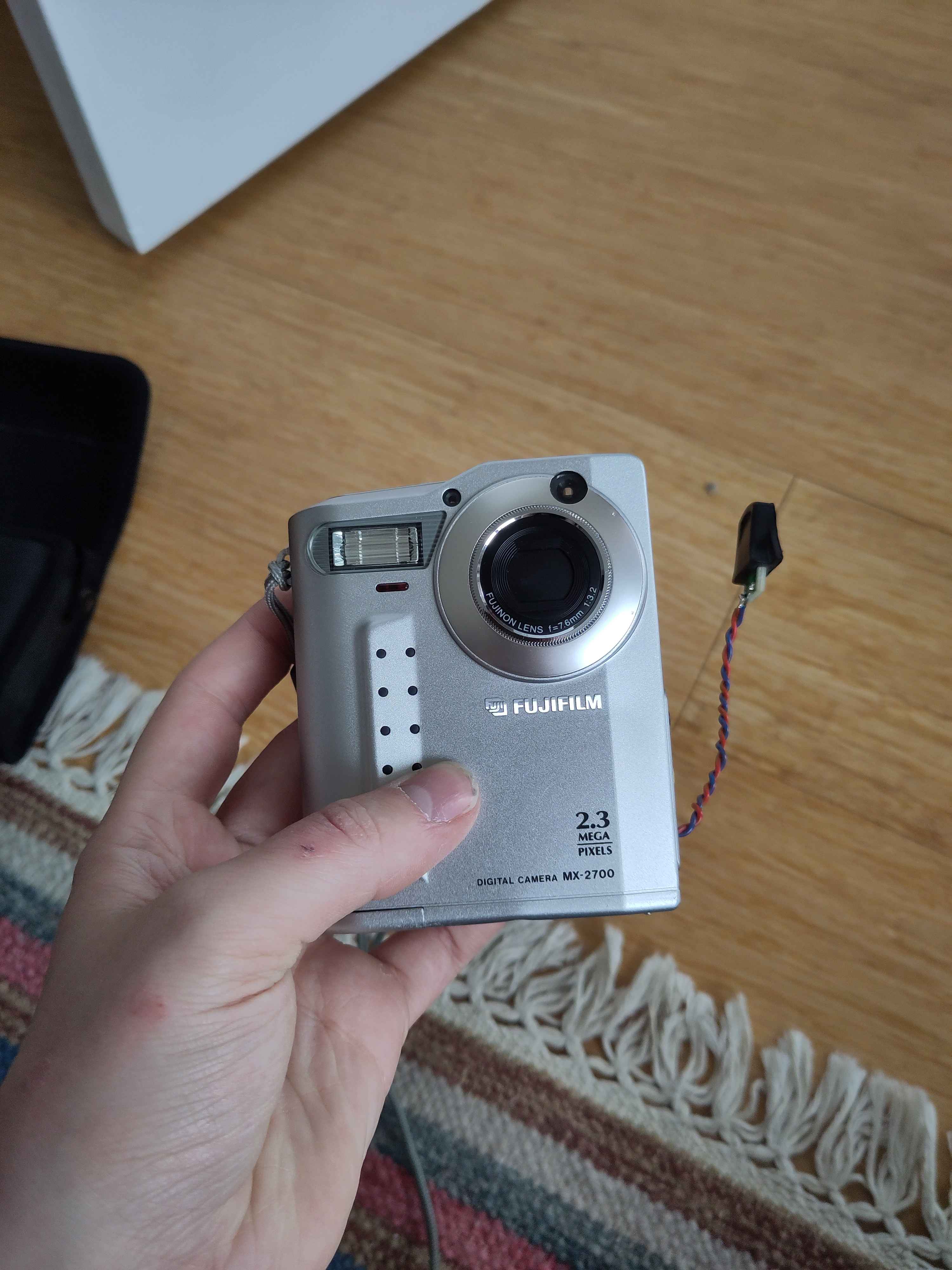 The front of a camera, it has a small rectangular body with a lense in the top right corner