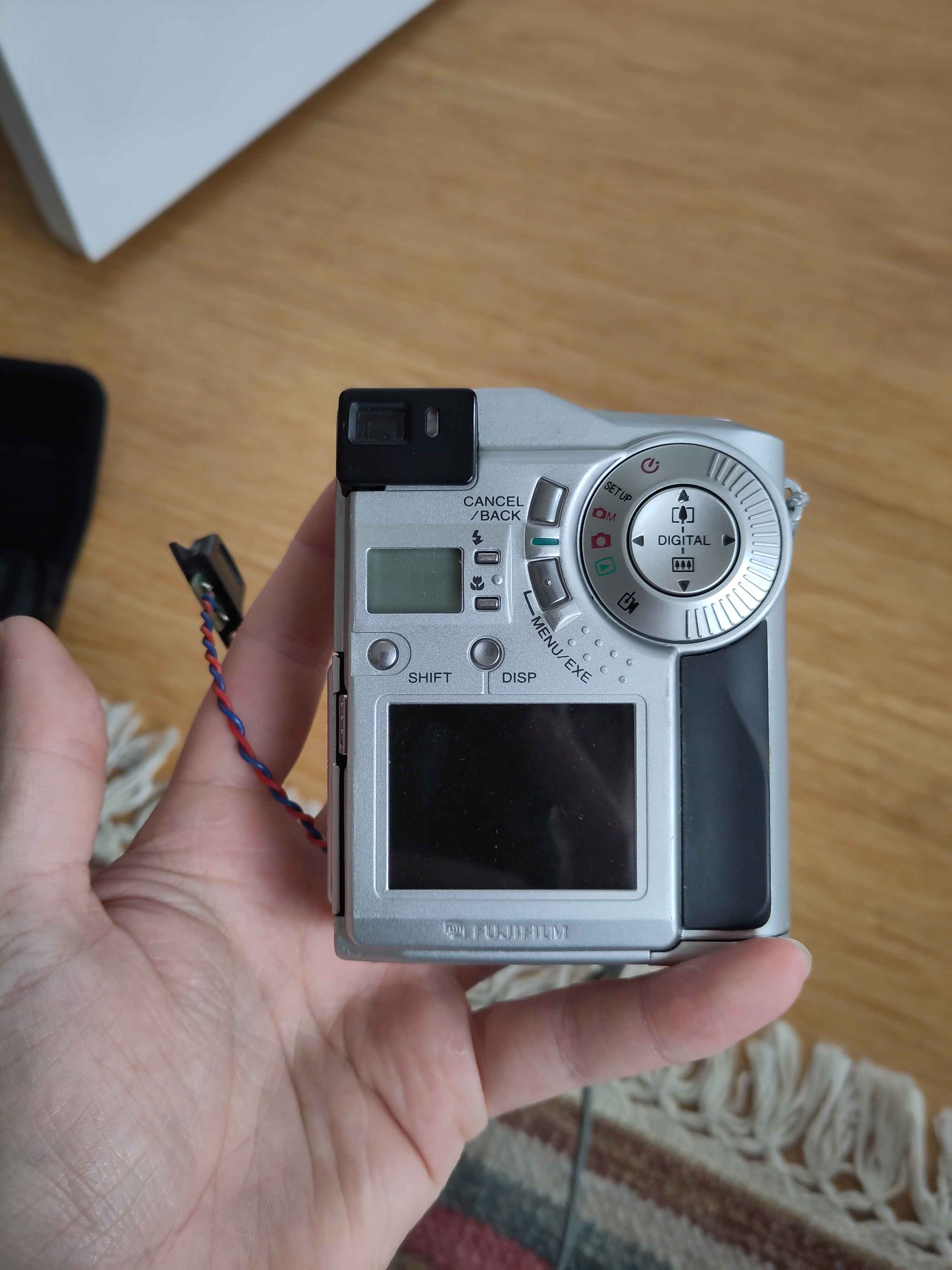 The back of a camera, it has a viewfinder in the top left corner, a small screen lcd screen and a dial to change its setting